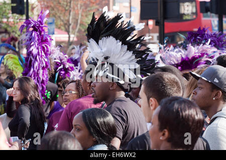 Folla a Hackney carnevale con giovane centro indossando una in bianco e nero di acconciatura di selvaggina di penna Foto Stock