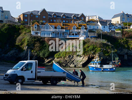 Due uomini manhanding un dinghy dal retro del camion di piccole dimensioni, Newquay, Cornwall, England Regno Unito Foto Stock