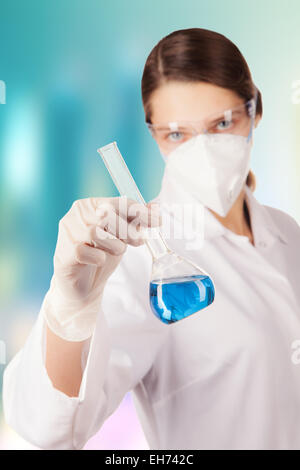 La donna nel laboratorio chimico di contenimento di liquido in pallone di vetro Foto Stock