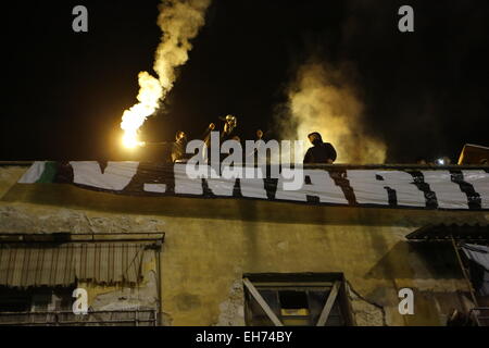 Atene, Grecia. 8 marzo 2015. Panathinaikos sostenitori hanno acceso razzi sul tetto di una casa accanto al Apostolos Nikolaidis Stadium. Gli appassionati di calcio greco club Panathinaikos F.C. guardare la partita contro FC PAOK Salonicco al di fuori del stadio vuoto. Tutti i giochi del round corrente della Superleague greca sono riprodotti in stadi vuoti dopo il campionato è stato sospeso dopo i tumulti. Credito: Michael Debets/Alamy Live News Foto Stock