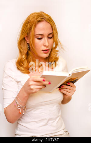 Giovane ragazza caucasica indossando t-shirt bianca con la lettura di libro isolato su uno sfondo bianco Foto Stock