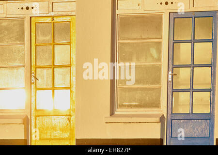 Giallo e Blu beach hut porte in alba luminosa luce solare Porthgwidden Beach St Ives Cornwall Inghilterra Europa Foto Stock