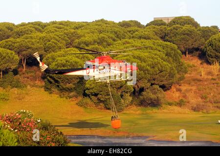 Bell 412 elicottero (registrazione N167EH) raccolta di acqua per la lotta contro gli incendi da un campo da golf lago, Cabopino Golf, Spagna. Foto Stock