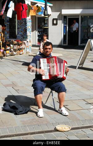 Il fisarmonicista pianoforte gioca per soldi in Main Street, Gibilterra, Regno Unito, Europa occidentale. Foto Stock