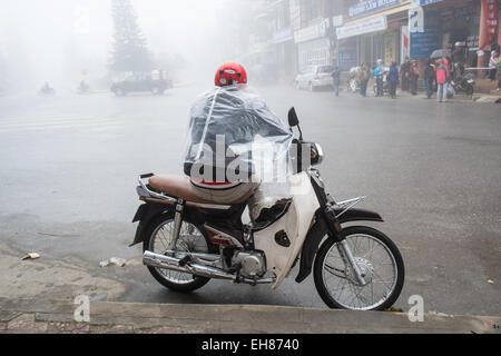 Scooter taxi rider attende una tariffa su un umido e nebbioso giorno in collina città della tribù di Sa Pa,Sapa,Vietnam, Foto Stock