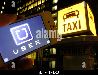 Berlino, Germania. 3 Mar, 2015. Illustrazione - un uomo possiede un iphone nelle sue mani che presenta il logo della cabina guida società 'uber', come egli stare accanto a una chiamata Taxi box a Berlino, Germania, 3 marzo 2015. UBER ha causato un agita tra autorizzati e stabiliti imprese di taxi come UBER driver sono accusati di pratiche anticoncorrenziali e non adhearing ai regolamenti. In diverse città in Germania, taxi gli imprenditori sono riusciti a ottenere diverse decisioni giudiziarie che limitano la uber di pratiche aziendali. Foto: Stefan Jaitner/dpa - nessun filo SERVICE -/dpa/Alamy Live News Foto Stock