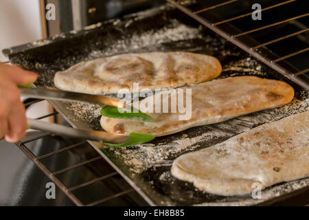 Il modo tradizionale per cuocere il pane Naan, un Indiano yeasted pane piatto, è in argilla o forno di terracotta, ma si possono cuocere in forno è un forno. Foto Stock