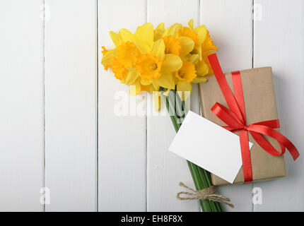Giunchiglie con una confezione regalo e una nota su un bianco sullo sfondo di legno Foto Stock