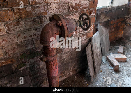 Rusty acqua tubazione di aspirazione con valvola di arresto in una fabbrica in disuso. Foto Stock