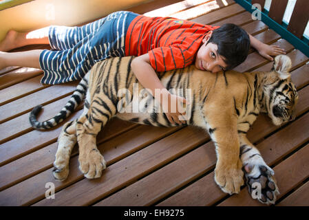 Un ragazzo che abbraccia un cucciolo di tigre in Chiang Mai la tigre del regno. Foto Stock