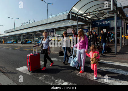 Passeggeri con bagagli e un bambino che cammina su un passaggio pedonale all'esterno del Terminal 1 dell'aeroporto Vaclav Havel di Praga. Foto Stock