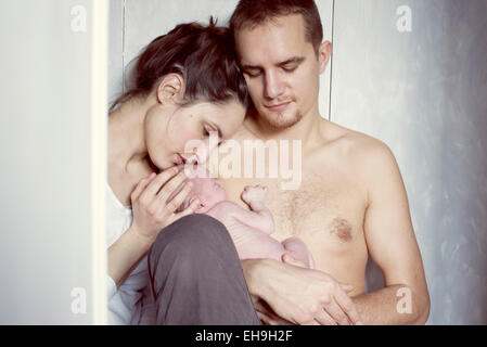 I nuovi genitori seduti con il neonato Foto Stock