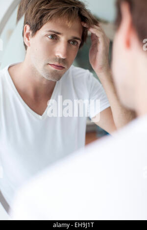 Uomo con receding hairline guardando a sé nel mirror Foto Stock