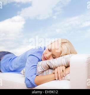 Sorridente giovane donna sdraiata sul divano Foto Stock