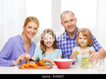 Felice famiglia con due bambini di preparare la cena a casa Foto Stock