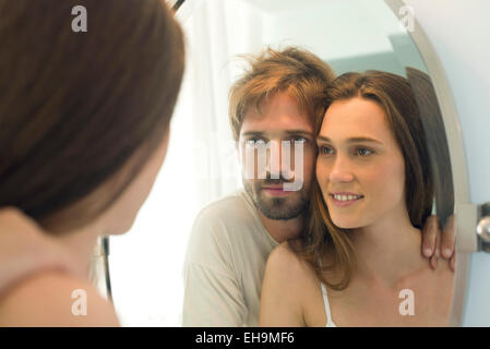 Giovane guardando nello specchio del bagno insieme Foto Stock