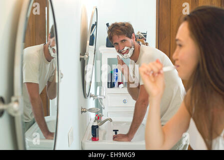 La donna la spazzolatura dei denti, marito la rasatura Foto Stock