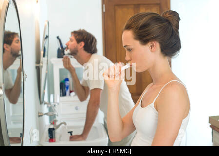 La donna la spazzolatura dei denti, marito la rasatura Foto Stock