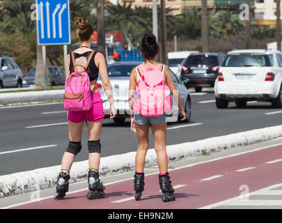 Due giovani donne con i rollerblade sulla pista ciclabile accanto alla città trafficata strada in Las Palmas di Gran Canaria Isole Canarie Spagna Foto Stock