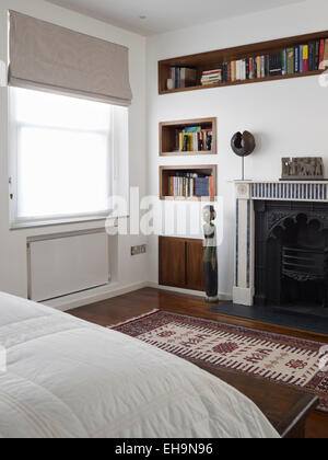 Inserto in legno scaffali con libri, sculture e antico caminetto in camera da letto di Cumberland Street Foto Stock