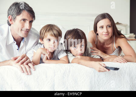 Famiglia di guardare la TV sul letto, ritratto Foto Stock