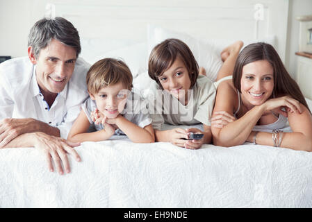 Famiglia di guardare la TV sul letto, ritratto Foto Stock