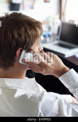 Lavoratore di ufficio tramite telefono cellulare, vista laterale Foto Stock