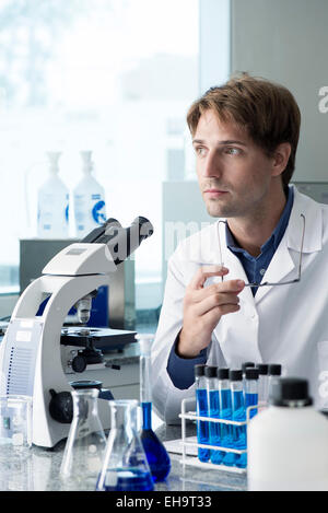 Scienziato che lavora in laboratorio, guardando lontano nel pensiero Foto Stock