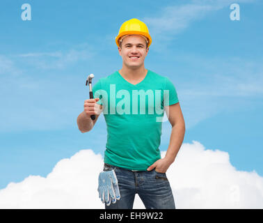 Sorridente lavoratore manuale nel casco con martello Foto Stock