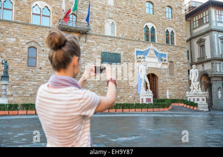 Giovane donna prendendo foto di Palazzo Vecchio a Firenze, Italia. vista posteriore Foto Stock