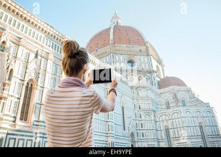 Giovane donna prendendo foto con tablet pc della cattedrale di Santa Maria del Fiore a Firenze. vista posteriore Foto Stock