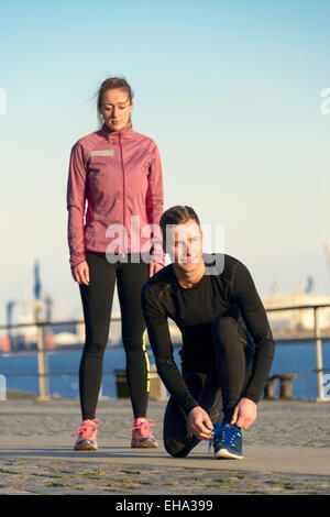 Coppia giovane in abiti di allenamento la preparazione per un Outdoor attività fitness al mattino. Foto Stock