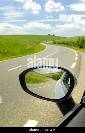 Specchio retrovisore di auto e strada tortuosa, Toscana, Italia Foto Stock