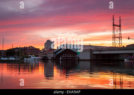 Un ponte levatoio salendo per una barca per passare sotto una rosa e arancione tramonto. Foto Stock