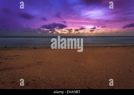Beach Sunrise in Fort Lauderdale, Florida, con una rosa e viola il cielo e una grande nave lontano all'orizzonte. Foto Stock