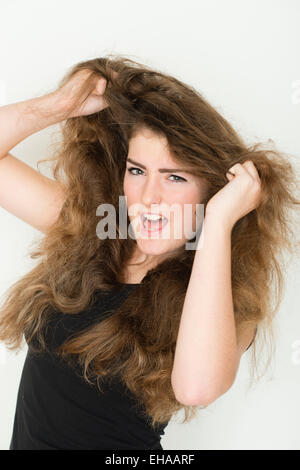 Un moody arrabbiato 13 14 enne ragazza adolescente lo strappo alla sua lunga marrone capelli grande REGNO UNITO Foto Stock