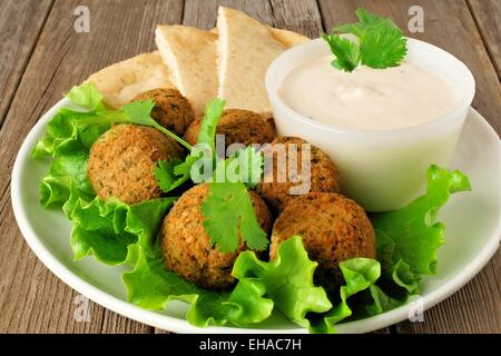 Piastra del falafel in insalata con pane pita e salsa tzatziki sul tavolo di legno Foto Stock