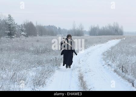 Esecuzione di samurai che indossa un kimono in un campo invernale vestita di nero, il gelo Foto Stock