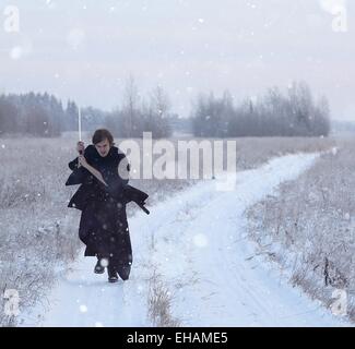 Esecuzione di samurai che indossa un kimono in un campo invernale vestita di nero, il gelo Foto Stock