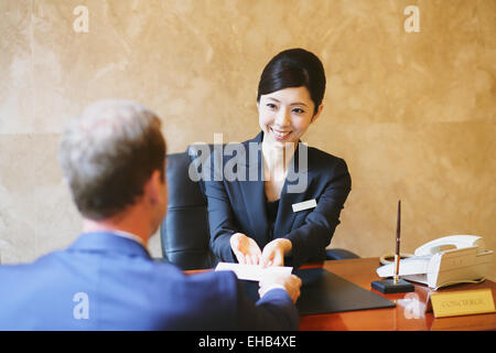 Femmina giapponese hotel concierge ha a che fare con un cliente Foto Stock