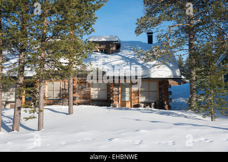 Un log cabin in Levi Lapponia Finlandia con neve e sole invernale. Utilizzato come inverno vacanze alloggio. Foto Stock