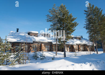 Un log cabin in Levi Lapponia Finlandia con neve e sole invernale. Utilizzato come inverno vacanze alloggio. Foto Stock