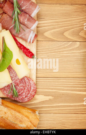 Formaggio, prosciutto, pane, spezie e verdure. Su un tavolo di legno con uno sfondo con spazio di copia Foto Stock