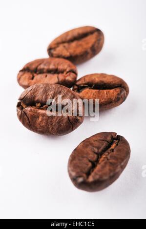 Close-up il caffè torrefatto in grani su sfondo bianco Foto Stock