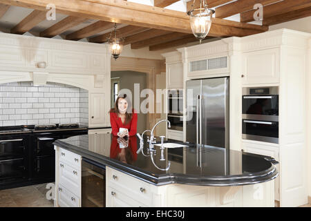 Donna matura in piedi di nuovo lusso Cucina attrezzata Foto Stock
