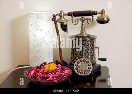 Un Vintage Telefono sul tavolo con fiori e lampada da tavolo. Foto Stock