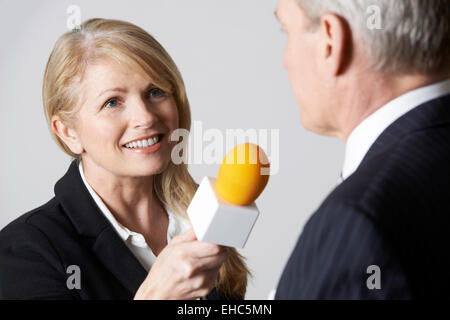 Giornalista con microfono intervistando il proprietario Foto Stock