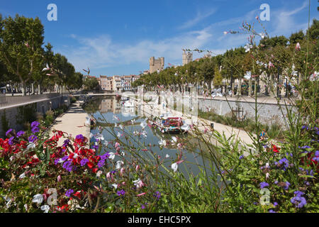 Il Canal du Midi a Narbonne, Aude nella Linguadoca Rossiglione Francia visto attraverso i fiori decorare un bridge crossing Foto Stock