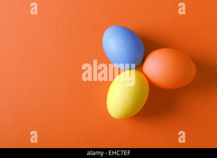 Tre dipinti di uova di pasqua su uno sfondo arancione Foto Stock