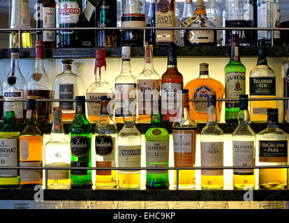 Selezione di whisky e altre bevande alcoliche su una accesa ripiano in vetro Foto Stock